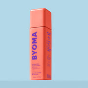 Une bouteille de tonique lacté hydratant Byoma, vue en angle montrant les étapes de routine « Boost Your Barrier » sur le panneau latéral, sur fond bleu.